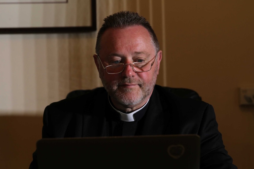 Father Rod Bower on his laptop