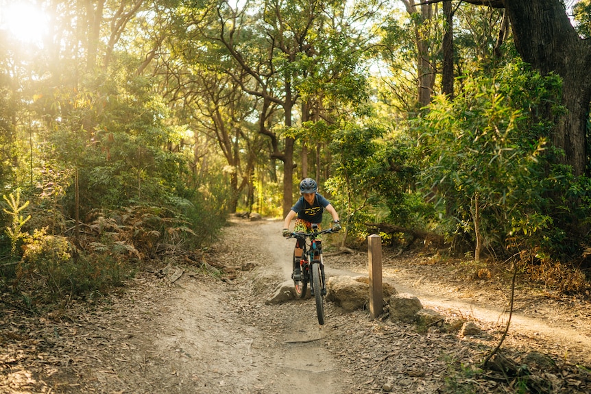 A boy jumps off a rock on a bike