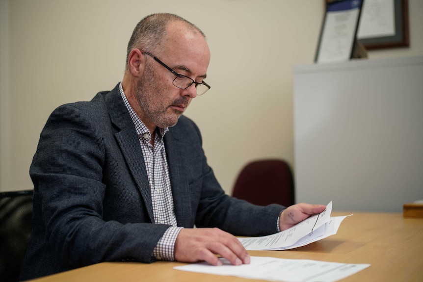 A man sitting at a desk reading documents.