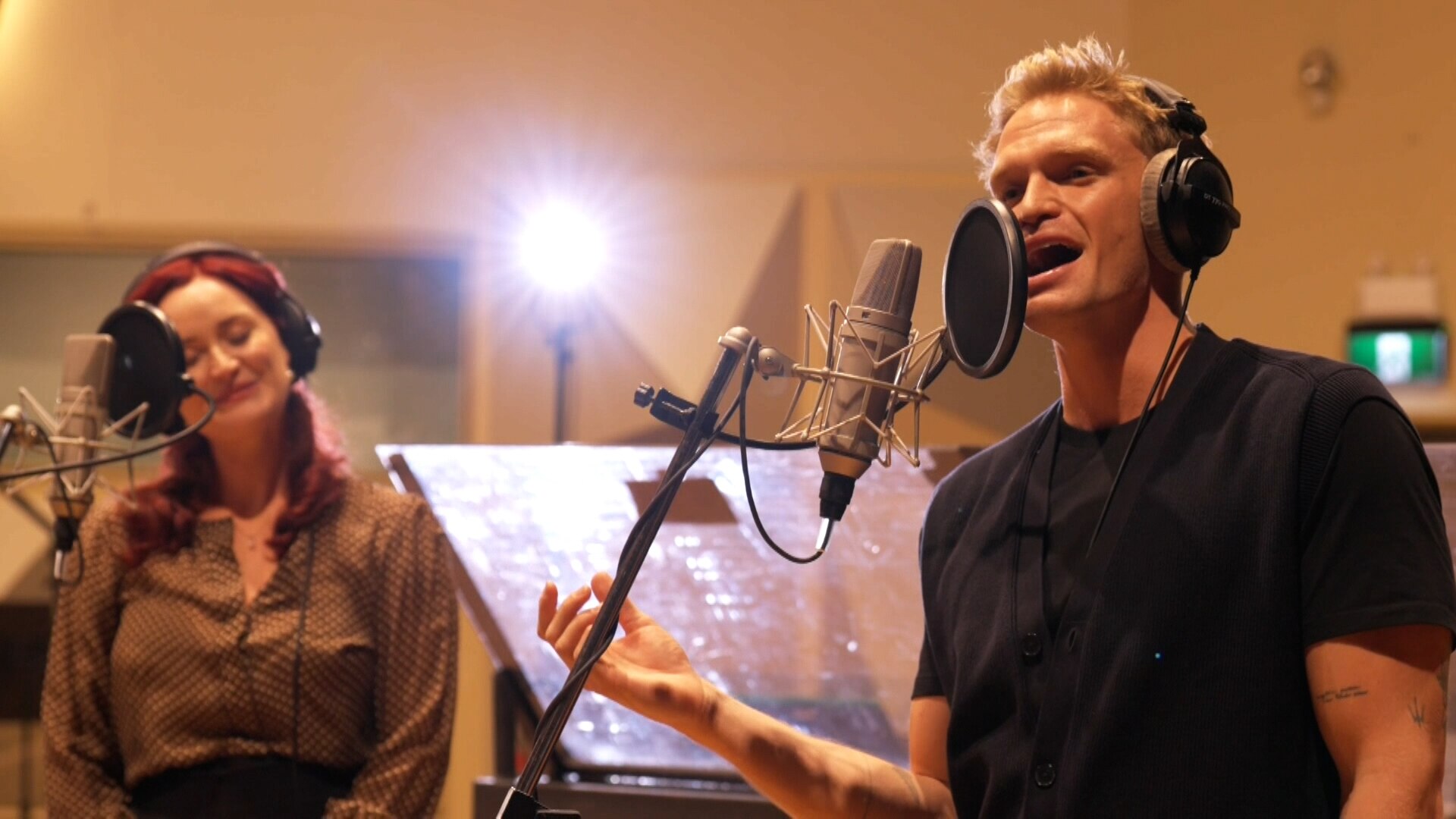 Cody Simpson sings in front of a microphone with fellow cast members of Guys & Dolls production