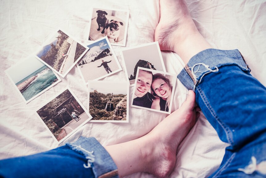 Photos on a bed with someone's feet in the picture