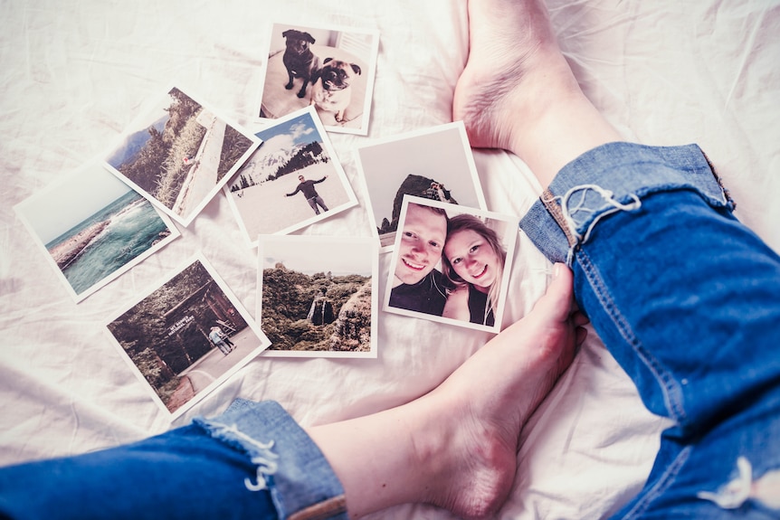 Photos on a bed with someone's feet in the picture