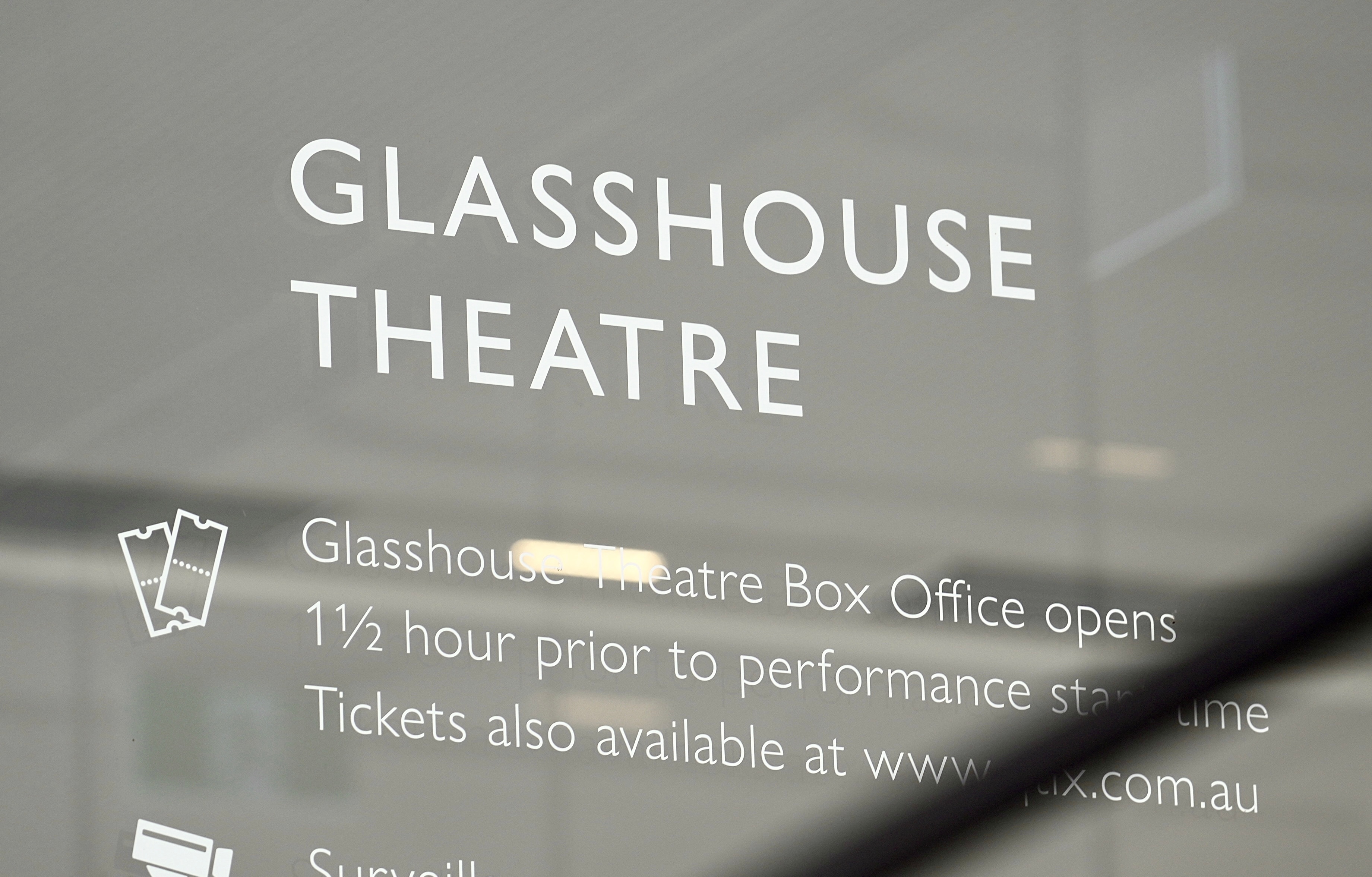 A sign for Glasshouse Theatre in white letters on glass.