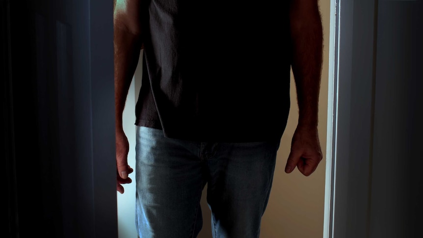 Man standing in a dark doorway with clenched fist