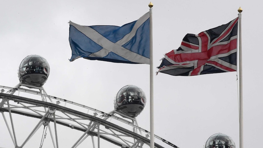 The British and Scottish Saltire flag fly above the Scottish Office in Whitehall, with the London Eye wheel seen behind.