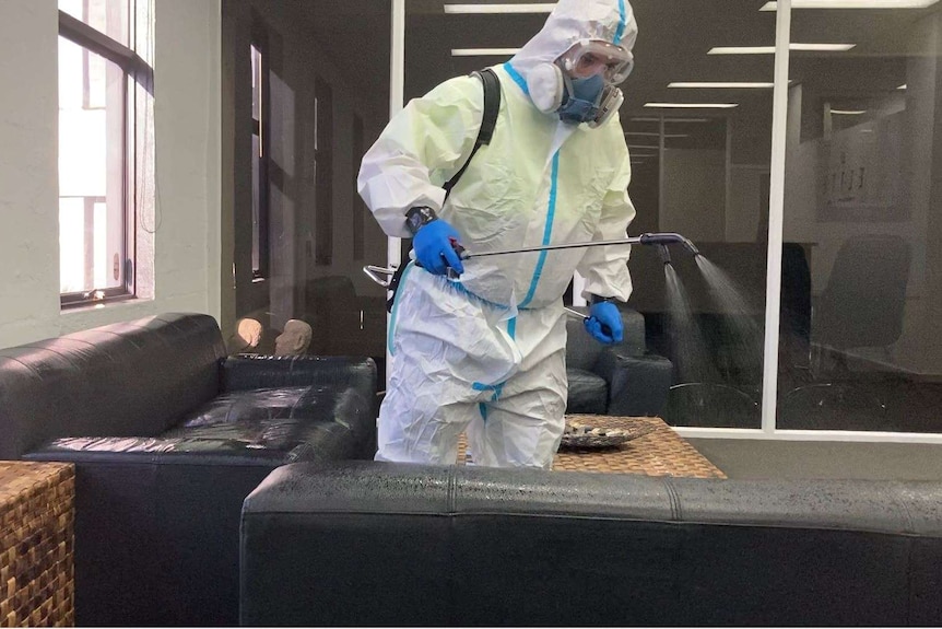 A cleaner sprays office furniture