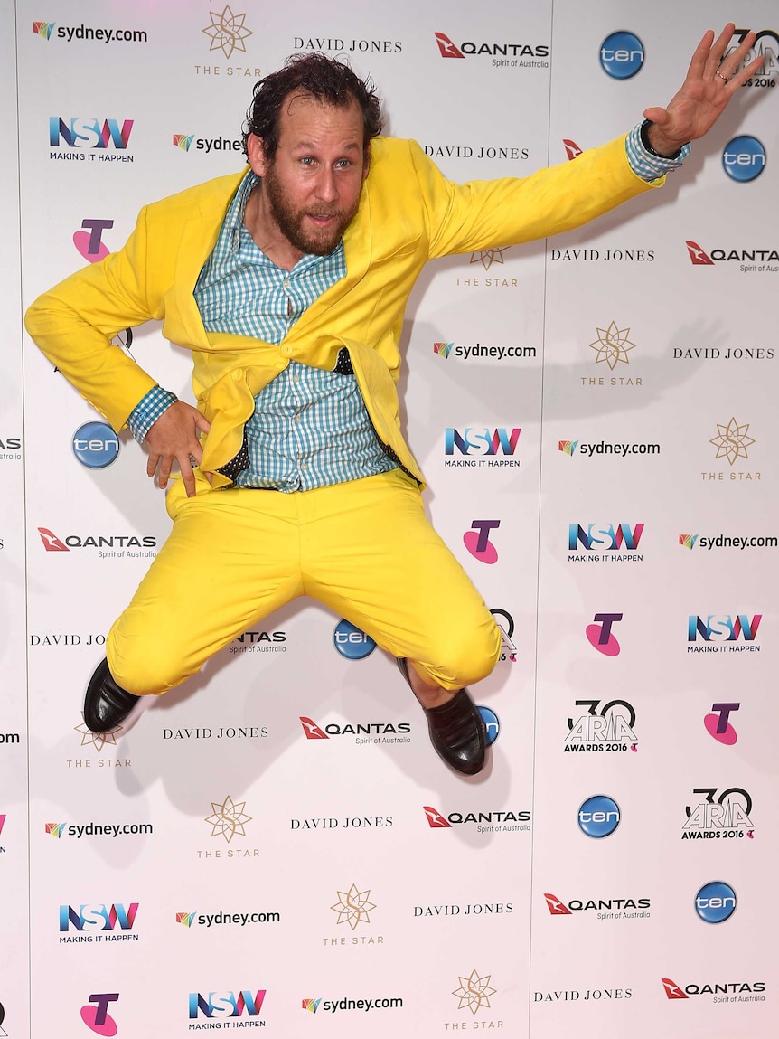 Ben Lee, wearing a yellow suit, jumps on the ARIA Awards red carpet
