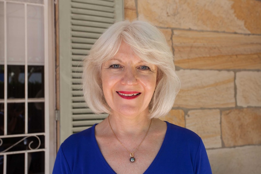 Chief executive of the Butterfly Foundation, Christine Morgan stands in front of a sandstone wall