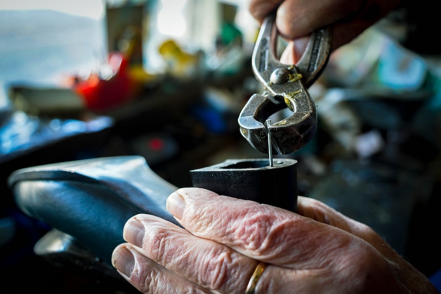 Close up of a hand and a shoe repair tool