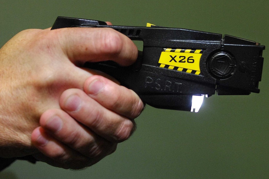 A police officer pointing a taser.