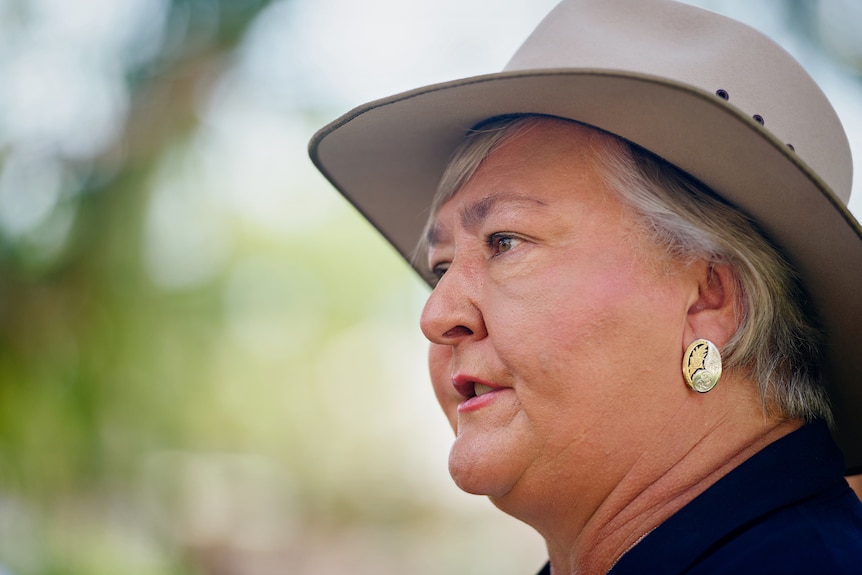 A close-up of former NT Senator Sam McMahon, wearing an Akubra, speaking to someone outside on a sunny day.