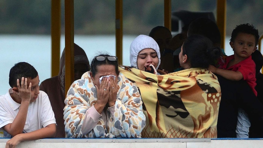 People who survived the capsizing of a ferry in Colombia cry and comfort one another as they wait for information.
