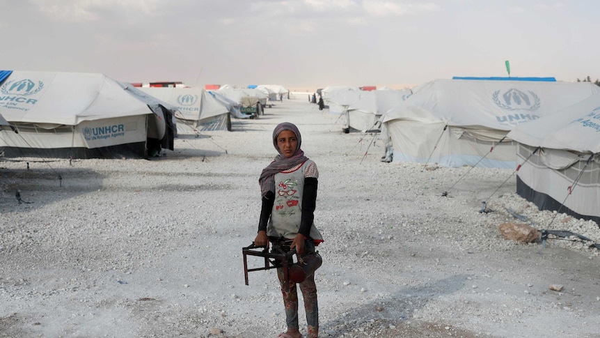 A teenager holds a cooker at a camp for people displaced amid UN tents in Ain Issa, Raqqa.