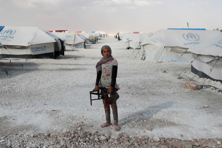 A teenager holds a cooker at a camp for people displaced amid UN tents in Ain Issa, Raqqa.