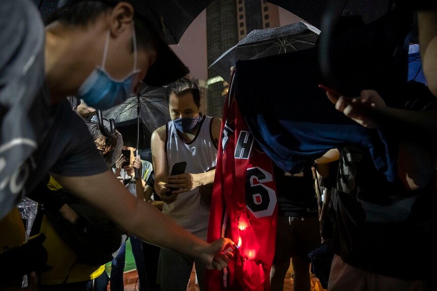 Protesters burning a basketball jersey on the street.