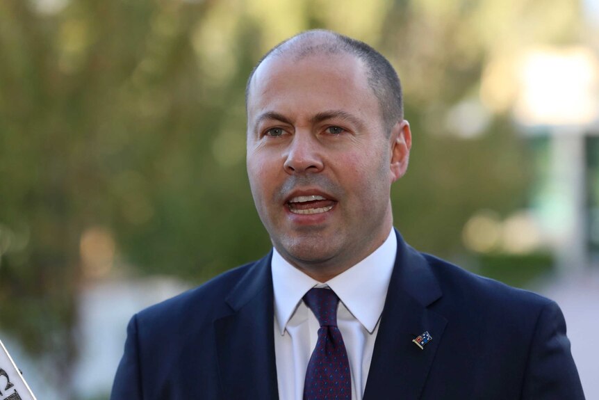 Josh Frydenberg wearing a navy suit with a maroon and blue tie and an Australia pin.