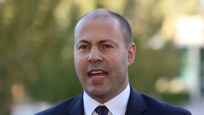 Josh Frydenberg wearing a navy suit with a maroon and blue tie and an Australia pin.