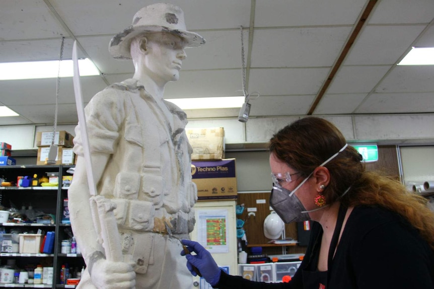 A woman working on the restoration of a statue of a soldier
