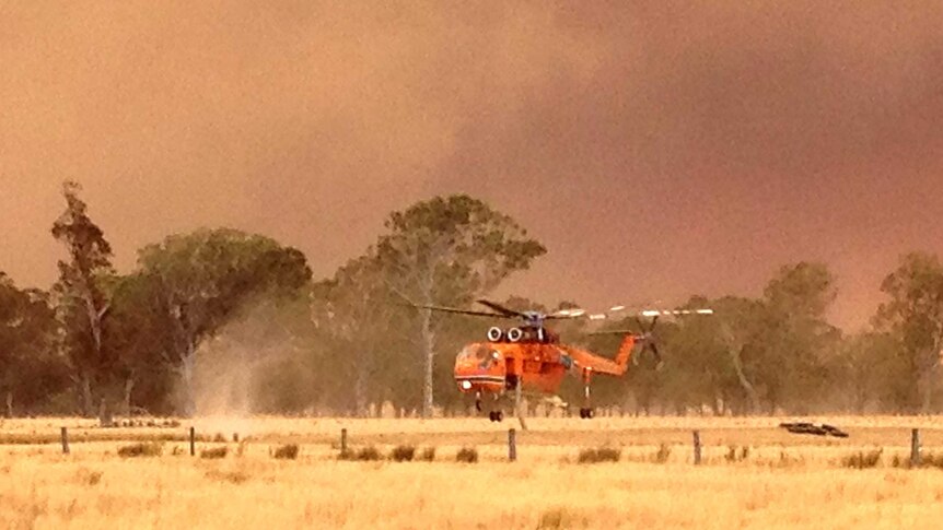 A helicopter fills with water before battling a bushfire.