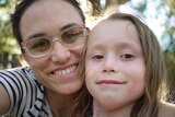 A close-up shot of a smiling woman in glasses and her daughter.