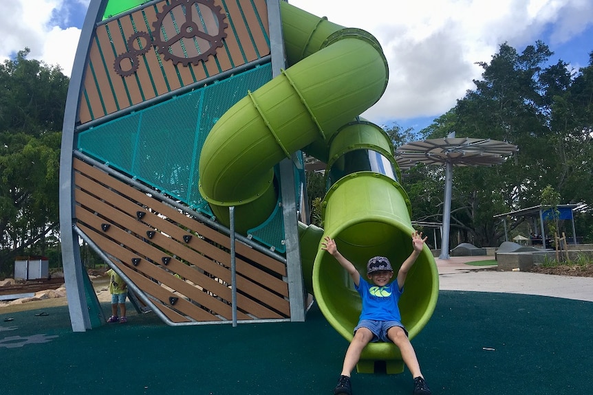 A child comes out of a tunnel on a piece of playground equipment