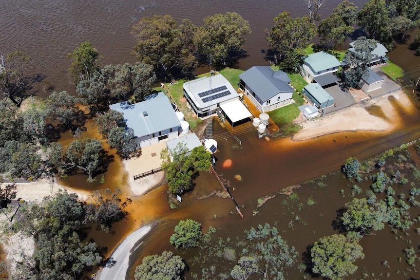 A birds eye view of brown river water reaching up to properties on the river's edge