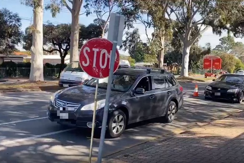 Cars waiting on a road behind a temporary stop sign