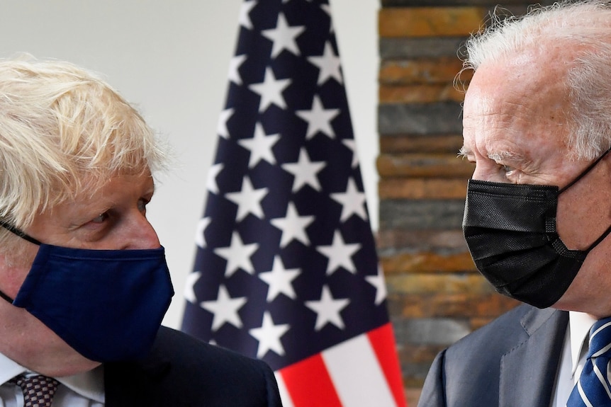 Joe Biden and Boris Johnson look at each other as they both wear face masks.