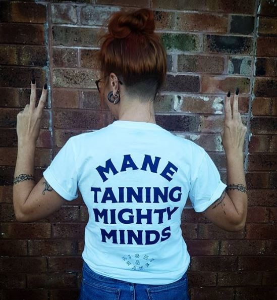 A woman with a shirt reading "mane taining mighty minds"