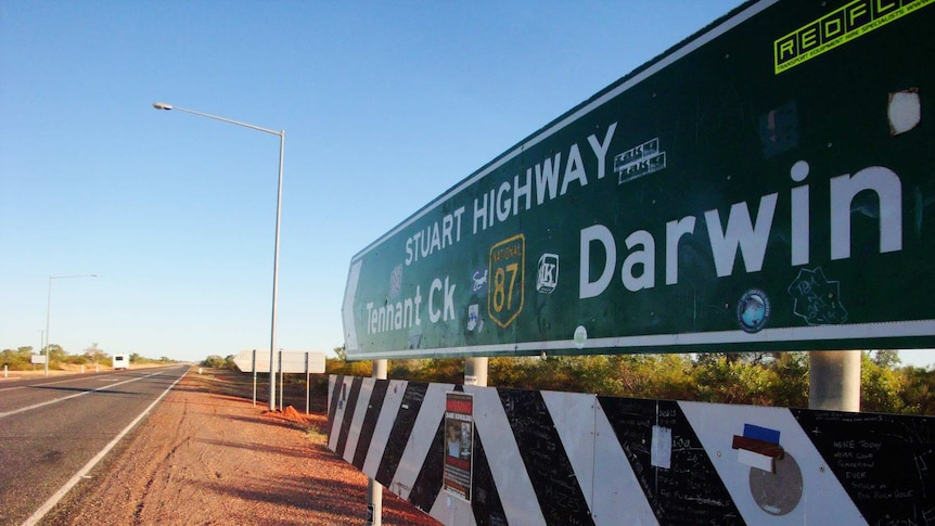 A large road sign up close, one end pointing to Tennant Creek, the other to Darwin