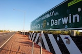 A large road sign up close, one end pointing to Tennant Creek, the other to Darwin