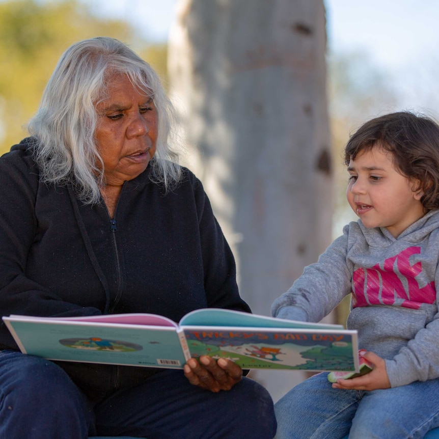 Woman  reads a picture book with a young girl