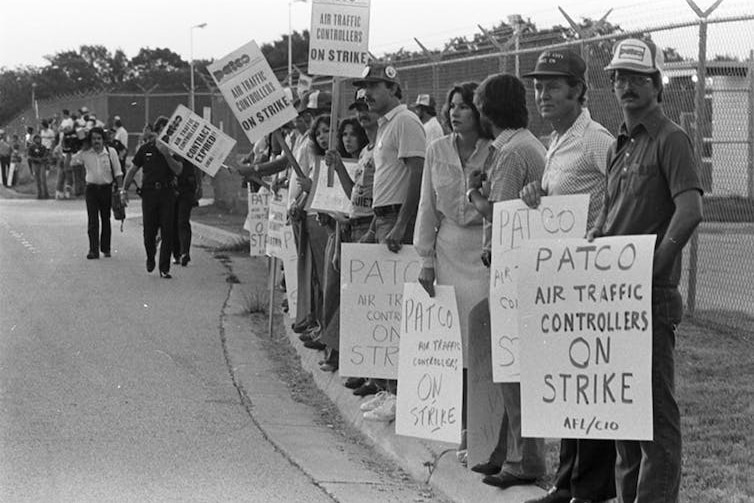 A black and white photo of striking air traffic controllers holding up signs. 