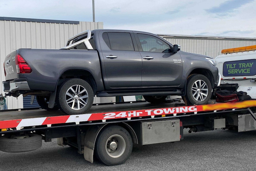 A grey Toyota Hylux on a tow truck.