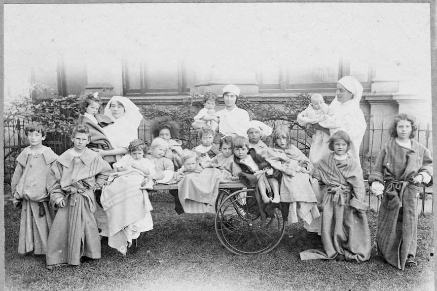 A black and white photo of children with nurses during the Spanish Flu pandemic.