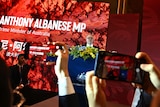 People holding up phones and taking photos of Albanese. 