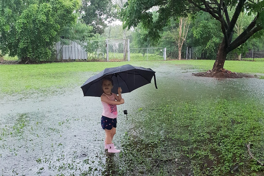 Toddler Evelyn Thomson holds an umbrella while playing in the puddles from the deluge at their home.