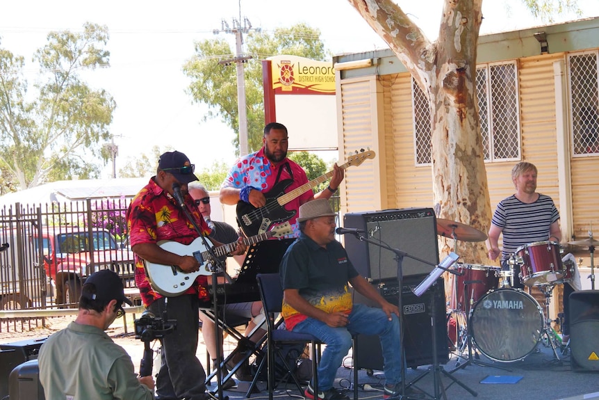 Five men on a stage playing music.