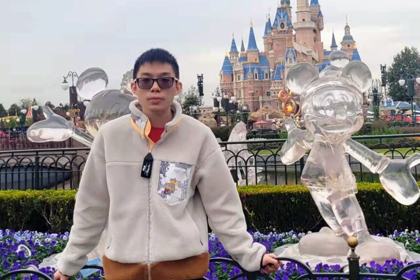 An Asian man is taking photo at Disney Land.