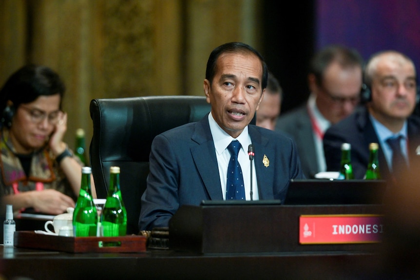 Joko Widodo sitting in front of a microphone 