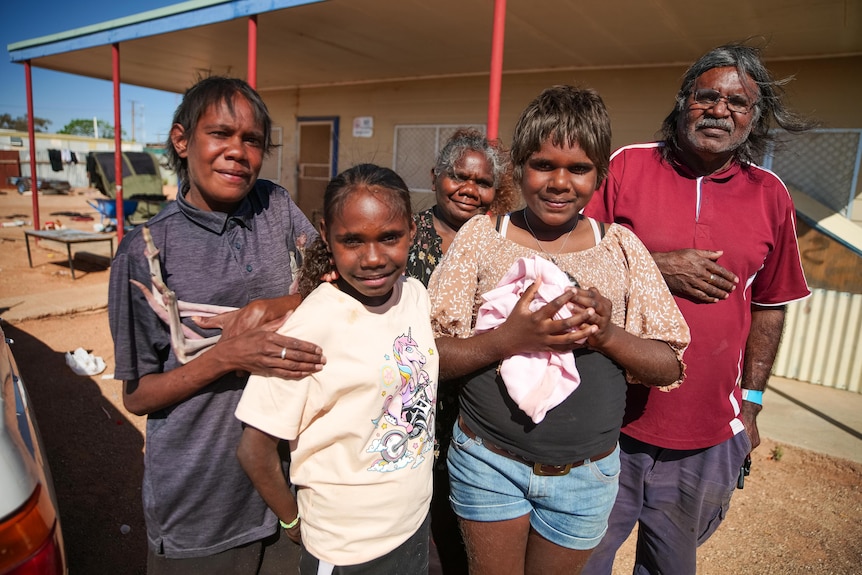 An Aboriginal family standing in front of their home