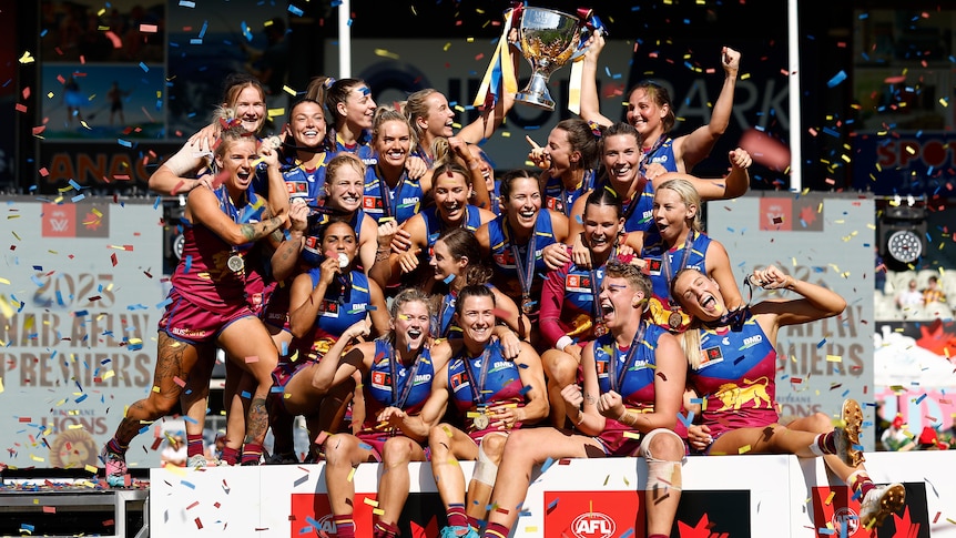 The Brisbane Lions celebrate with the AFLW premiership cup.
