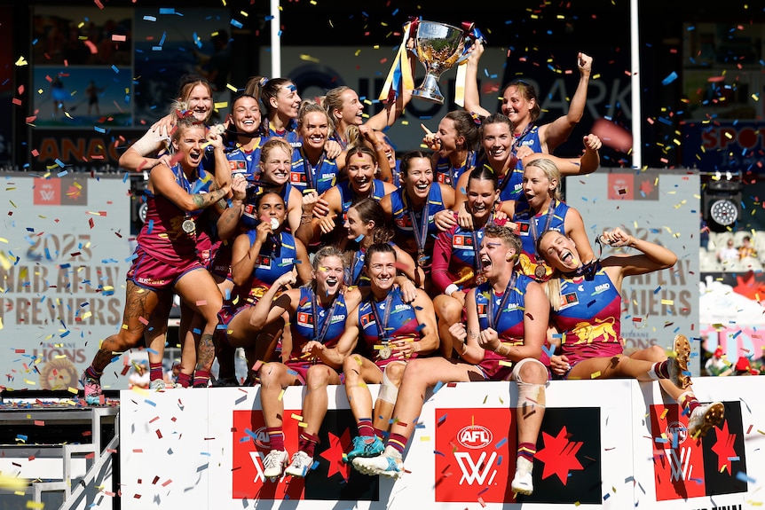 The Brisbane Lions celebrate with the AFLW premiership cup.