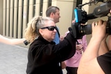 A woman places her hand on a television camera