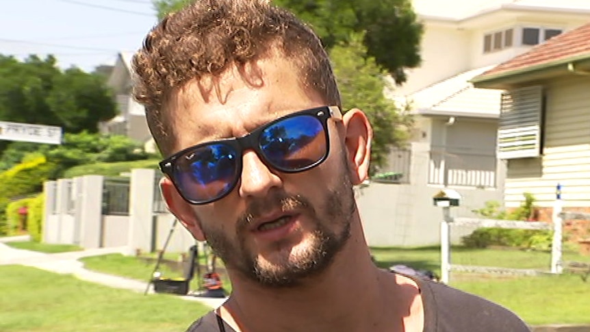 A young man in sunglasses speaking to reporters