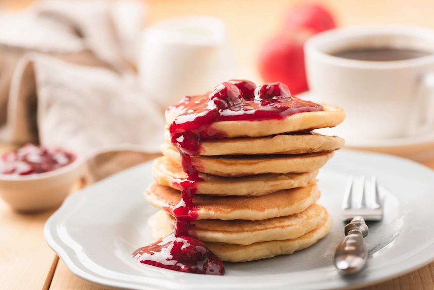 a stack of pancakes covered in rasberry sauce