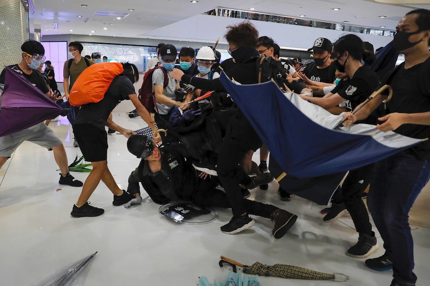 A policeman is attacked by angry protesters inside a mall.