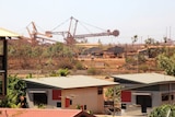 Huge mining machinery with houses in the foreground.