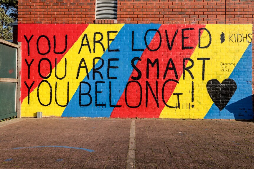 A multi coloured mural on a brick wall that reads You are loved, You are Smart, You Belong