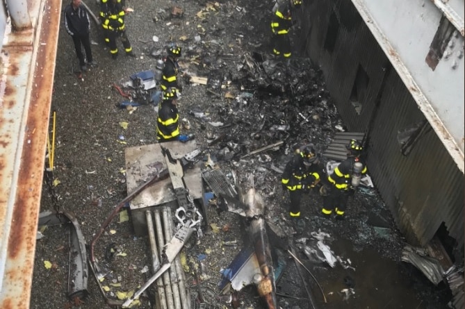 Image from above shows firefighters looking through charred debris.